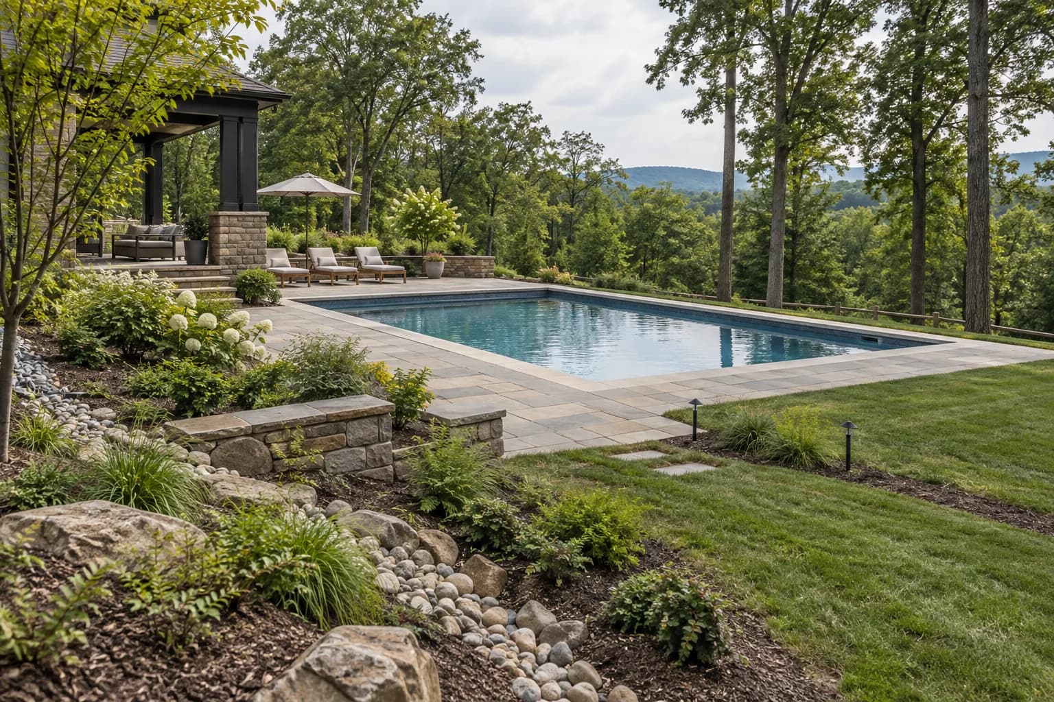 Pool on a wooded sloping property with drainage swale, modest retaining work, and mature trees